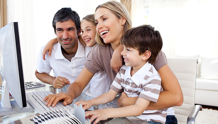Eine junge Familie sitzt am Computer.